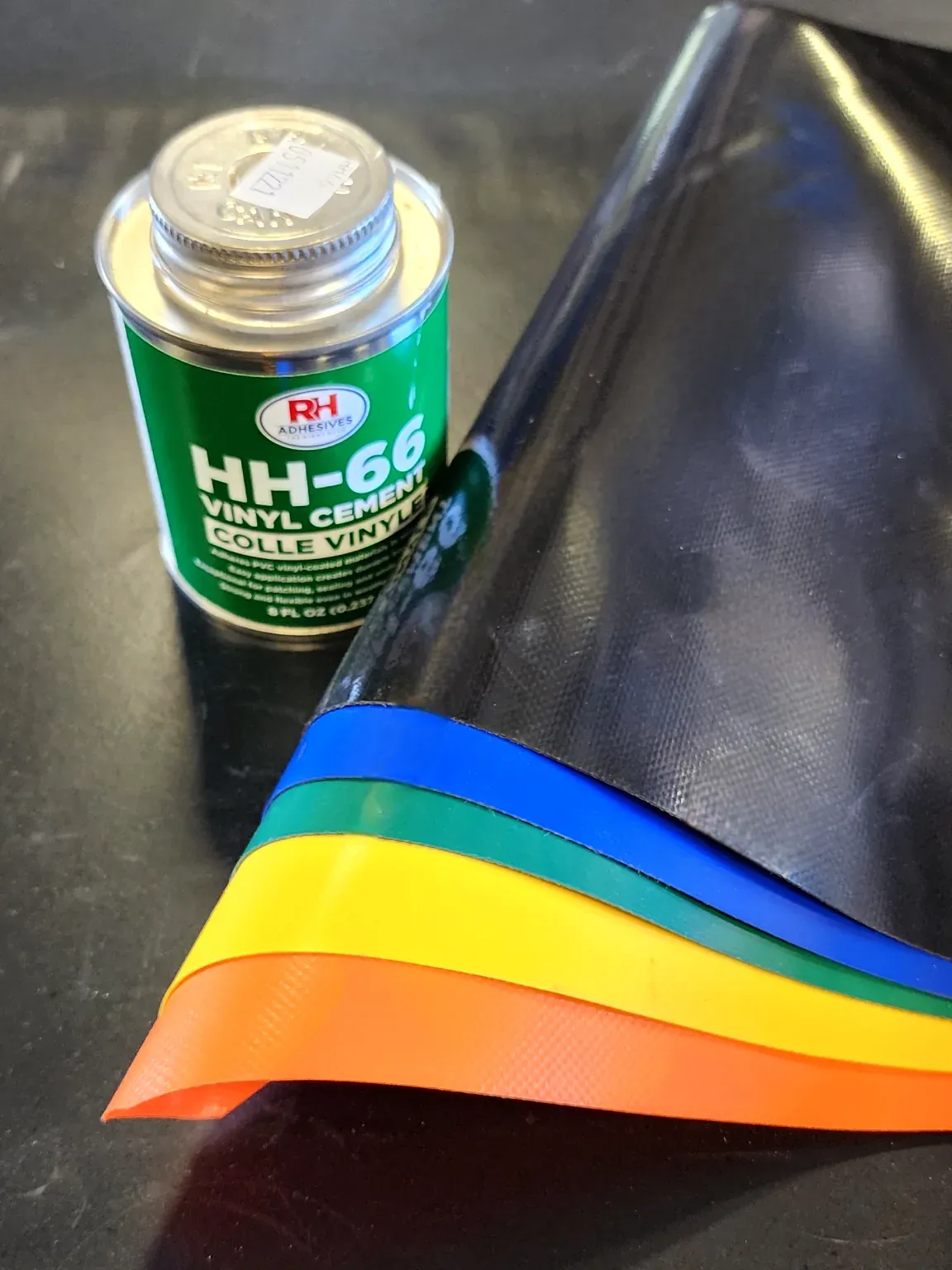 Vinyl cement used for tarp repair, beside a tarp edge