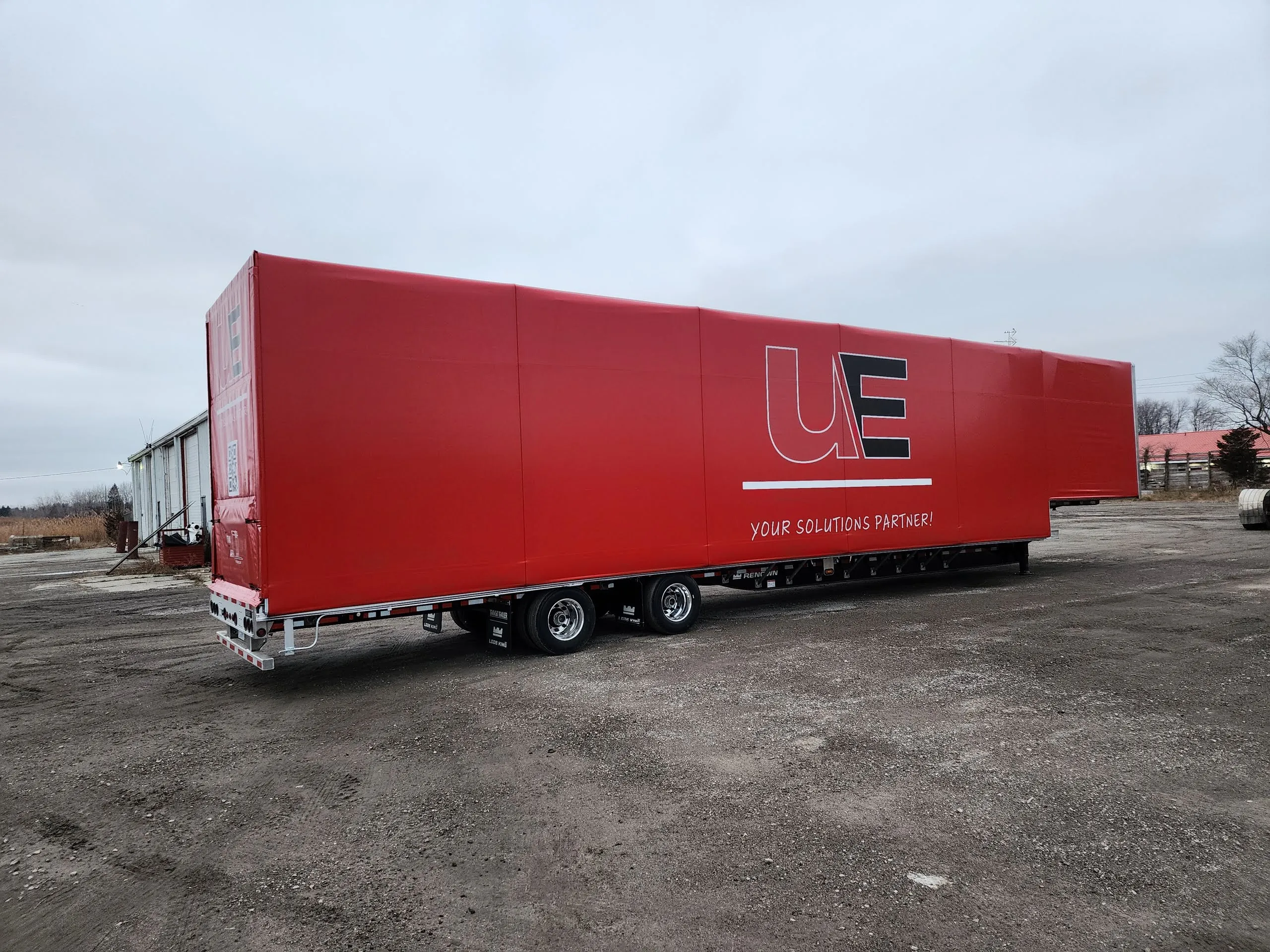 A step deck trailer covered by a red Titan sliding tarp system