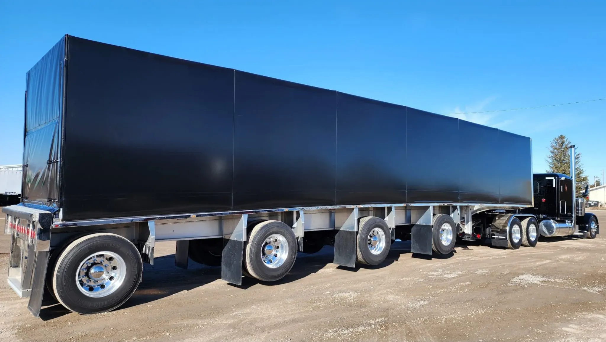 A black Titan sliding tarp system fitted to a flatbed trailer