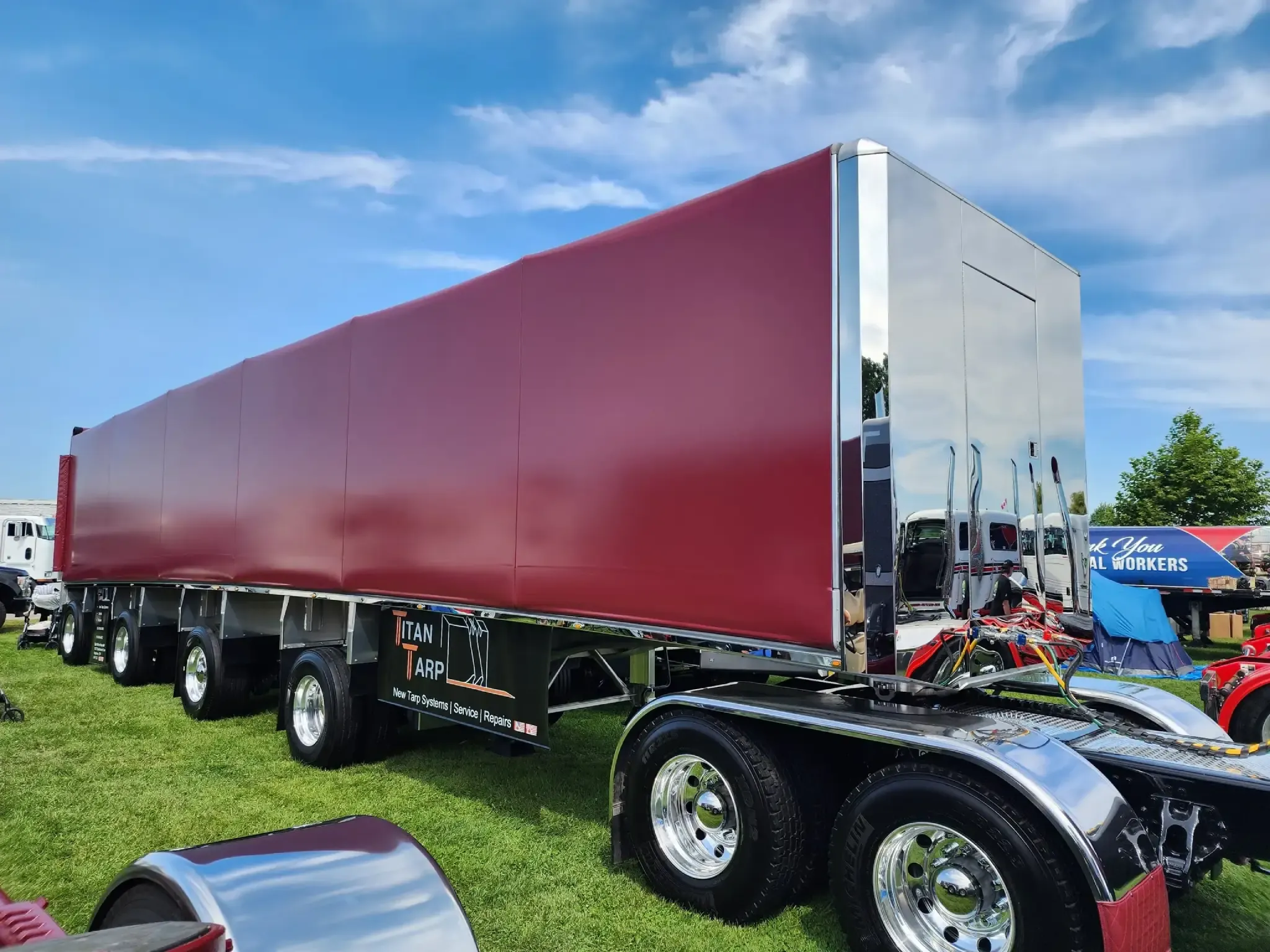 A Titan tarp system in red vinyl on a polished flatbed trailer